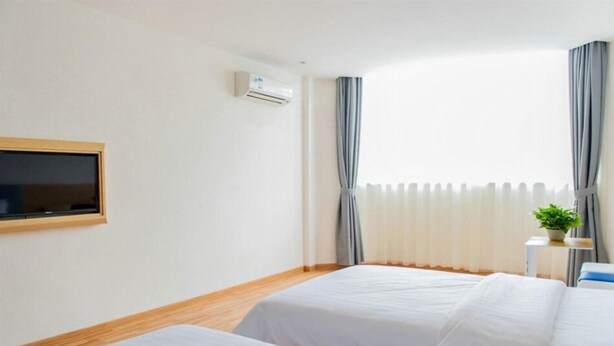 A hotel room with two beds, a TV mounted on the wall, an air conditioning unit, and a window with curtains. - 7 Days Inn Harbin Railway Station Qiulin Shop (Harbin)