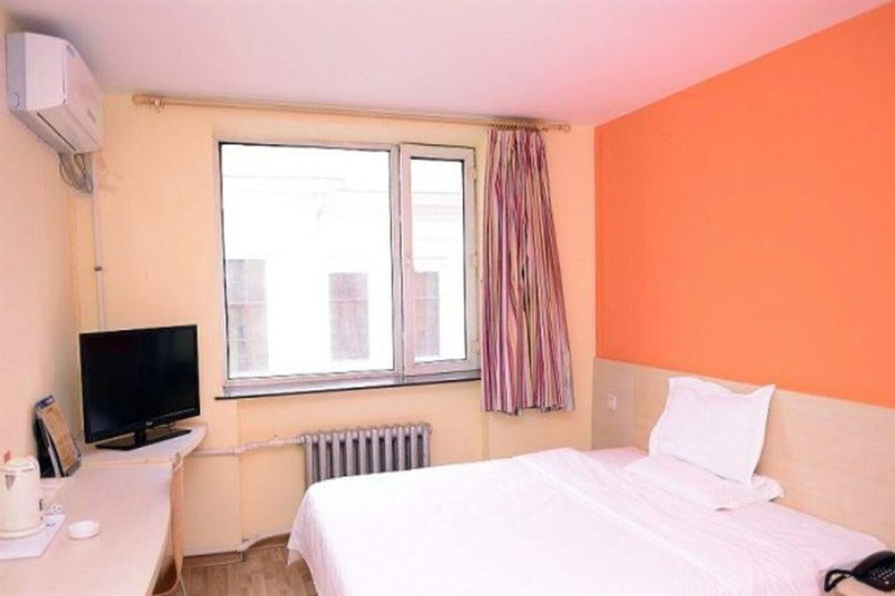 Une chambre d’hôtel avec un lit, un bureau équipé d’un ordinateur, une télévision et une fenêtre avec des rideaux.