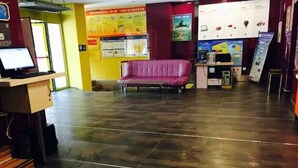 Un vestíbul amb una taquilla d'informació, un sofà morat i cartells informatius a les parets.