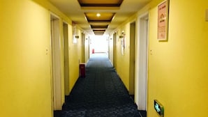 Passadís d'hotel amb parets grogues, un mosaic de moqueta i portes a ambdós costats que donen a habitacions.