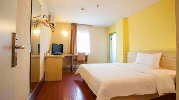 A hotel room with a bed, desk, chair, television, and a mirror.