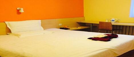 A hotel room with a bed, a desk, and a chair.