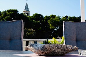A view of a church steeple with a cross on top, surrounded by lush green trees. - Villa Tonika (Selca)
