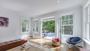 A spacious living room with a brown leather sofa, a blue chair, and a wooden floor. - Mansion Near the Bay. 7 bedrooms! Chef’s kitchen. (Southampton)
