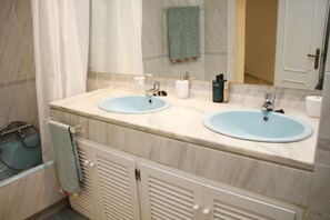 A bathroom with two sinks, a towel rack, and a shower area.