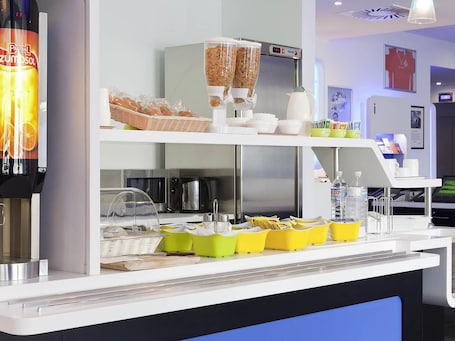 A breakfast bar with a cereal dispenser, baskets of bread, and a coffee machine.