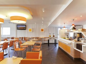Un restaurante moderno con una barra larga, varias zonas de estar y una pantalla de televisión en la pared.