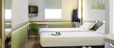 Una habitación de hotel con una cama, un escritorio, una silla, un televisor y una ventana.