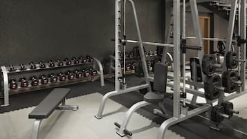 A gym with weightlifting equipment, a bench, and a rack of dumbbells.