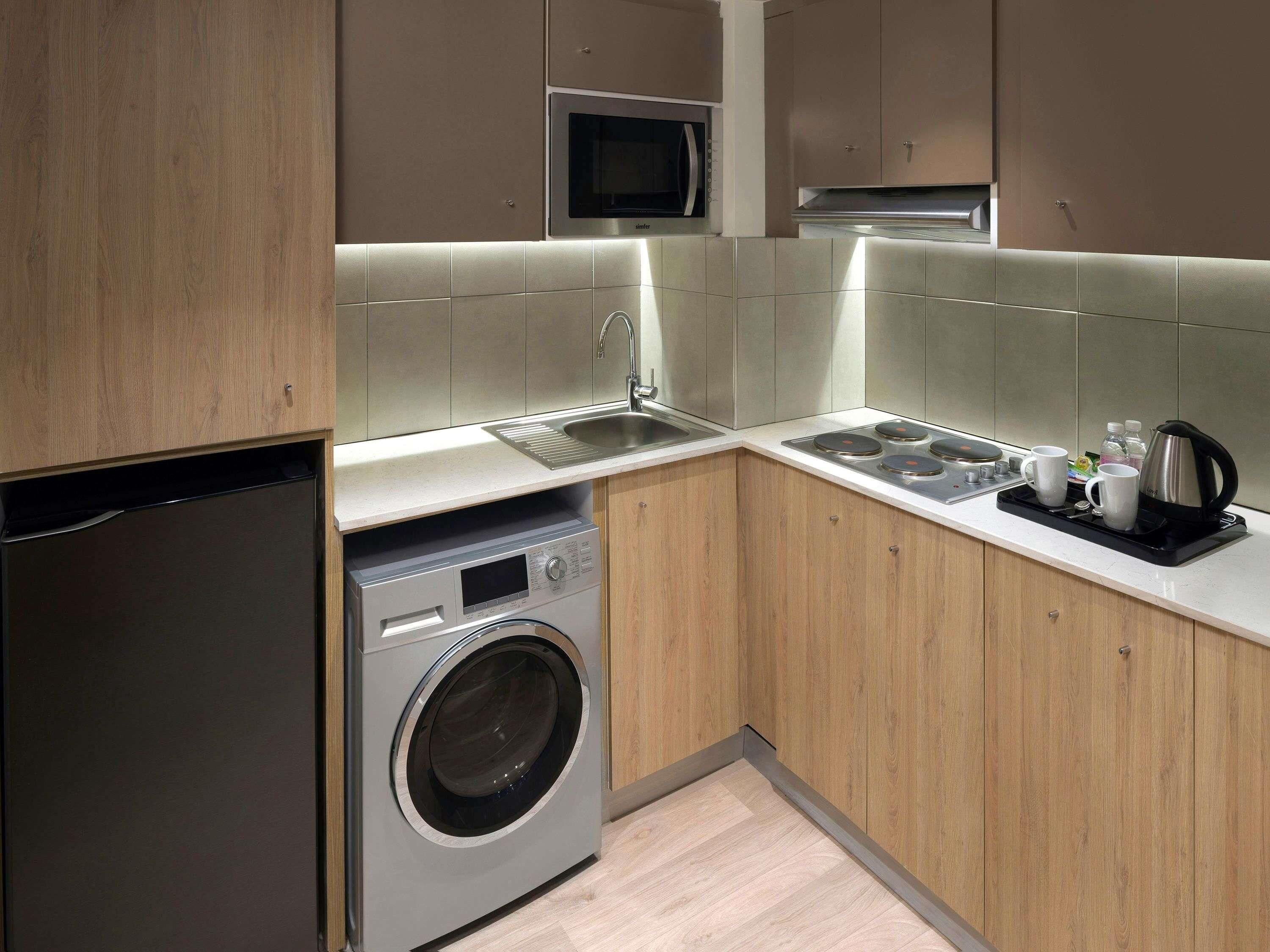 Een moderne keuken met een ingebouwde wasmachine, roestvrijstalen apparatuur en een koffiezetapparaat.