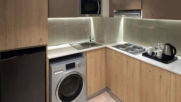 Een moderne keuken met een ingebouwde wasmachine, roestvrijstalen apparatuur en een koffiezetapparaat.