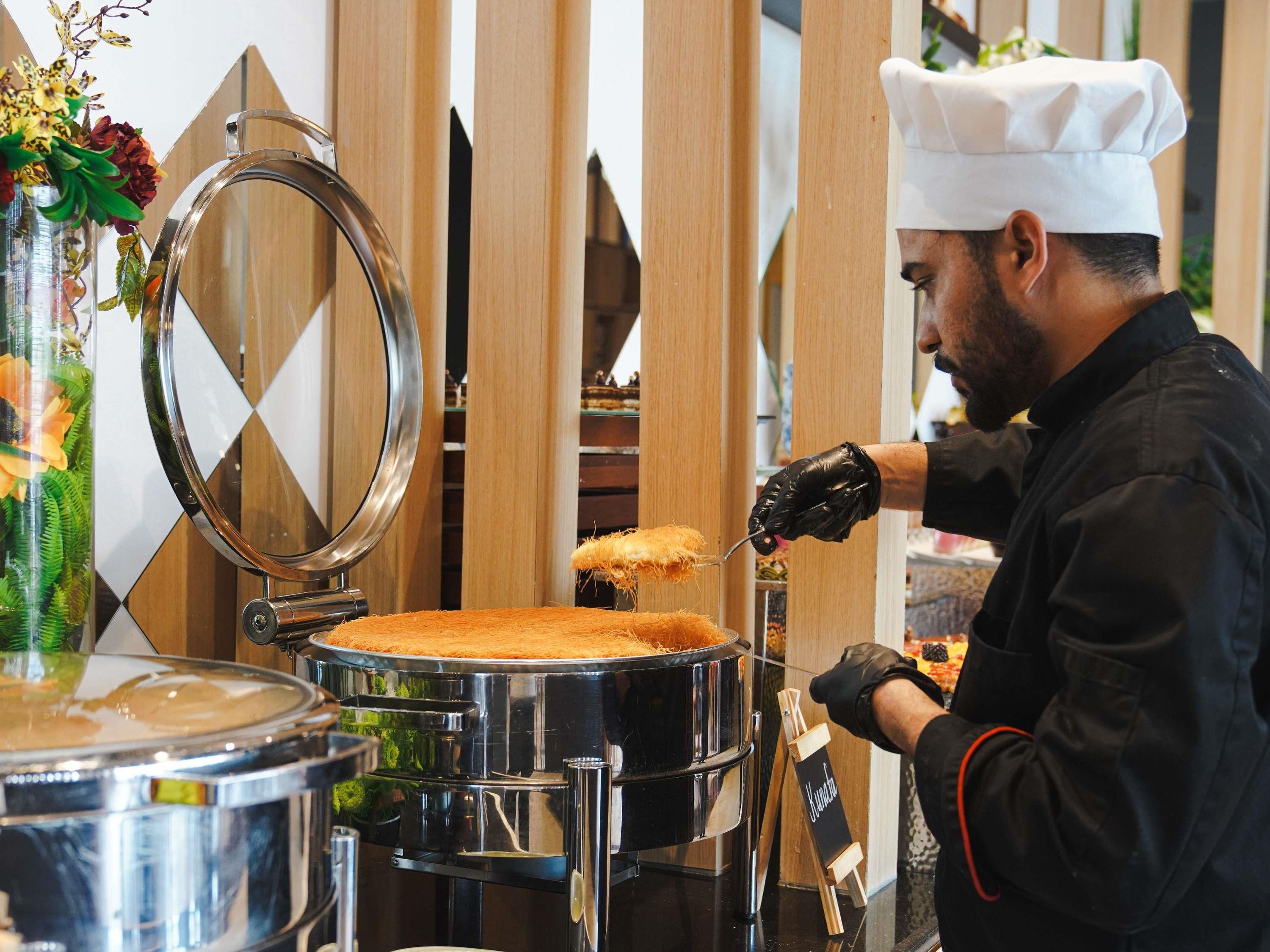 A chef preparing food in a kitchen with stainless steel equipment and wooden accents.