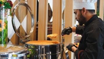 A chef preparing food in a kitchen with stainless steel equipment and wooden accents.