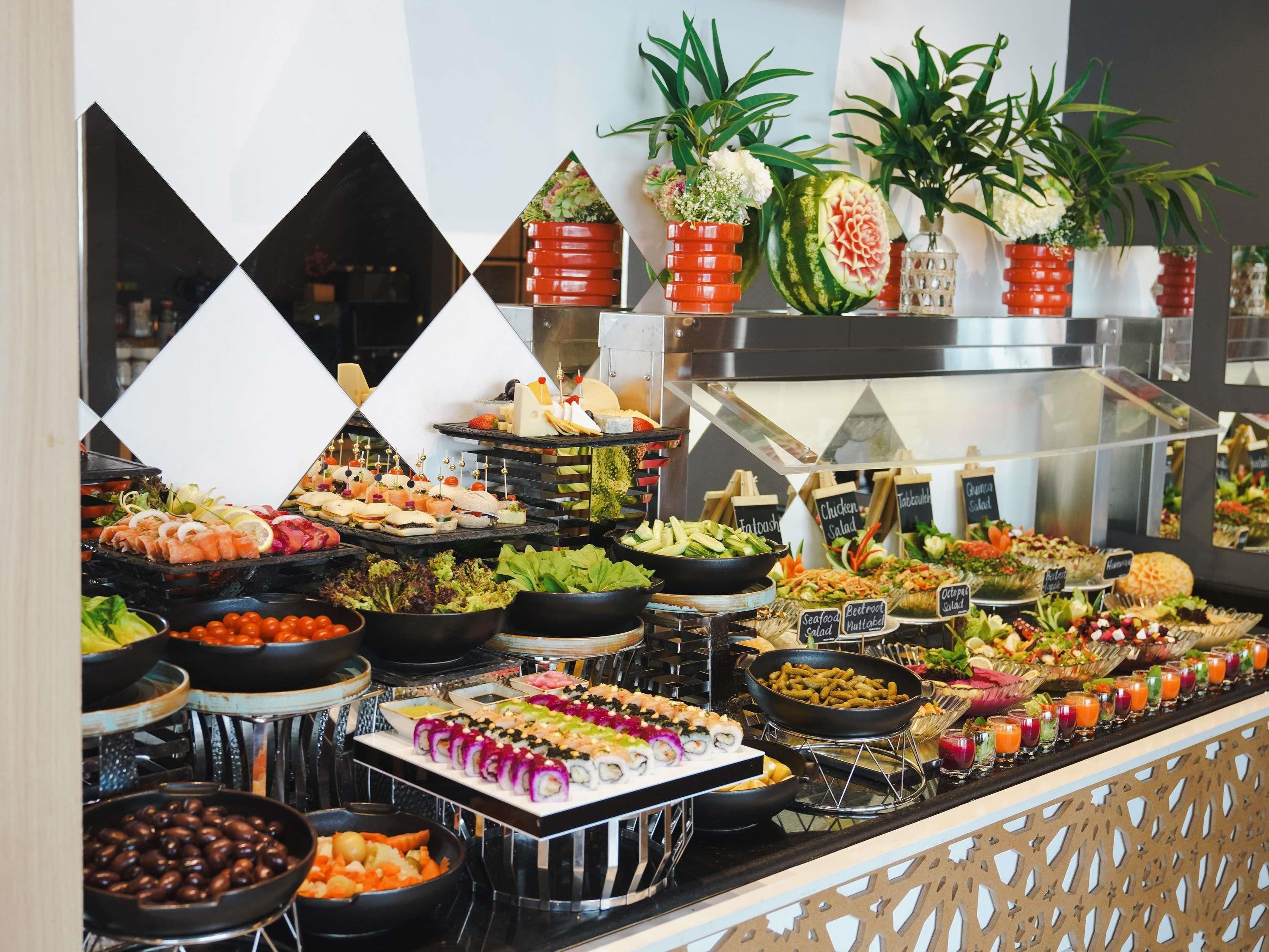 A buffet with various food items and a decorative wall with geometric patterns.