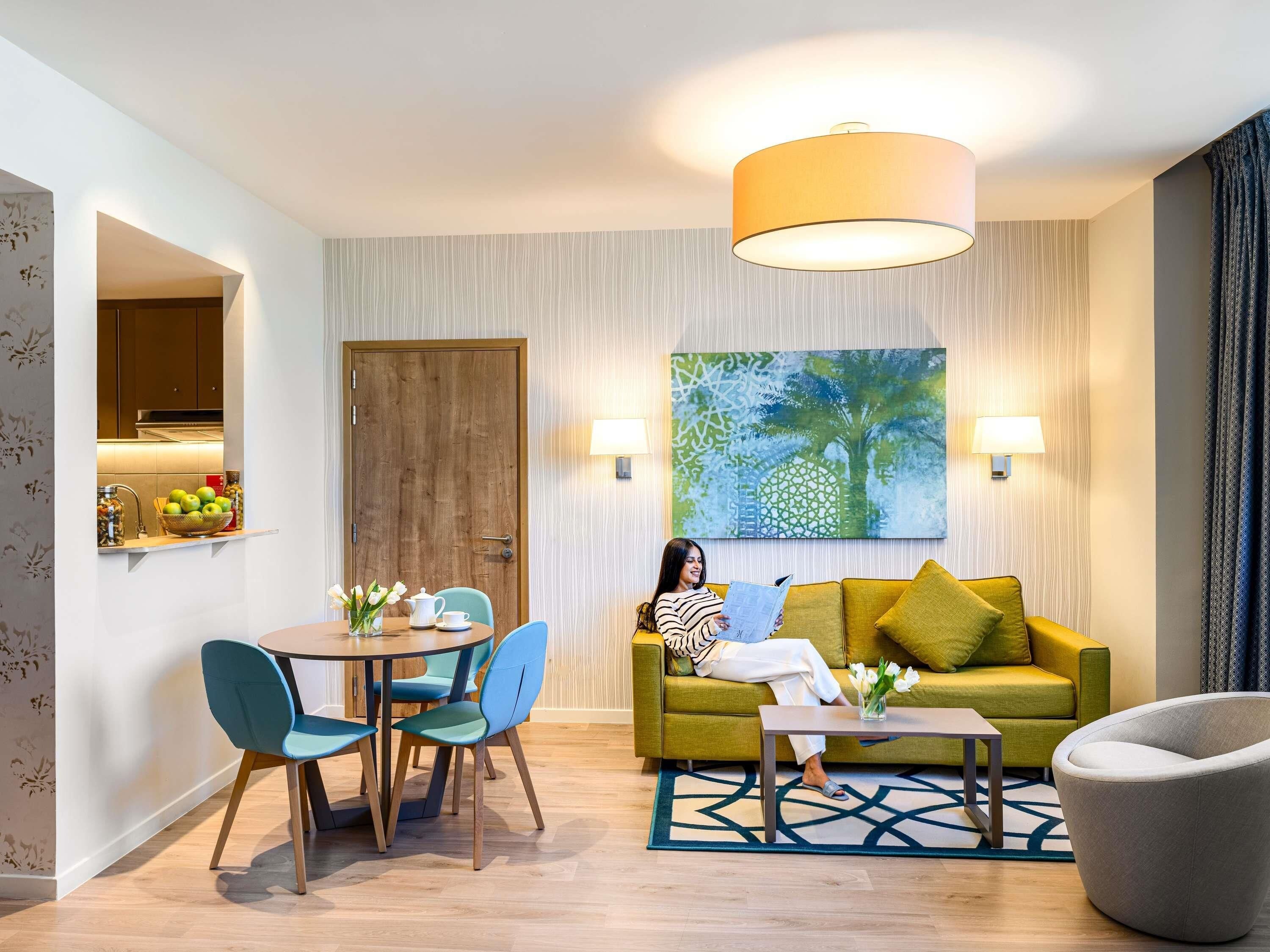 A modern living room with a sofa, a coffee table, and a dining area with chairs.