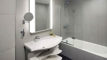 Un baño moderno con un espejo grande, un lavabo blanco, una bañera y una ducha.