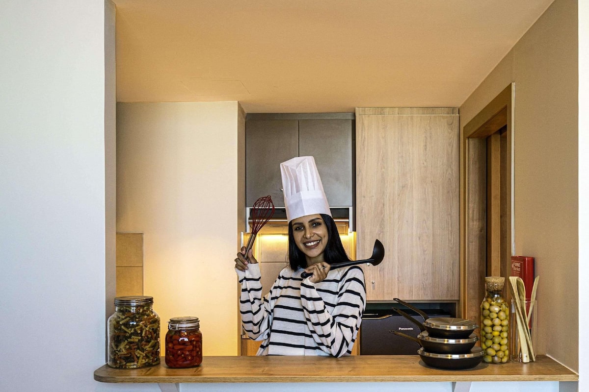 A kitchen with a wooden countertop, jars of preserved food, a pan, and a bottle of olive oil.