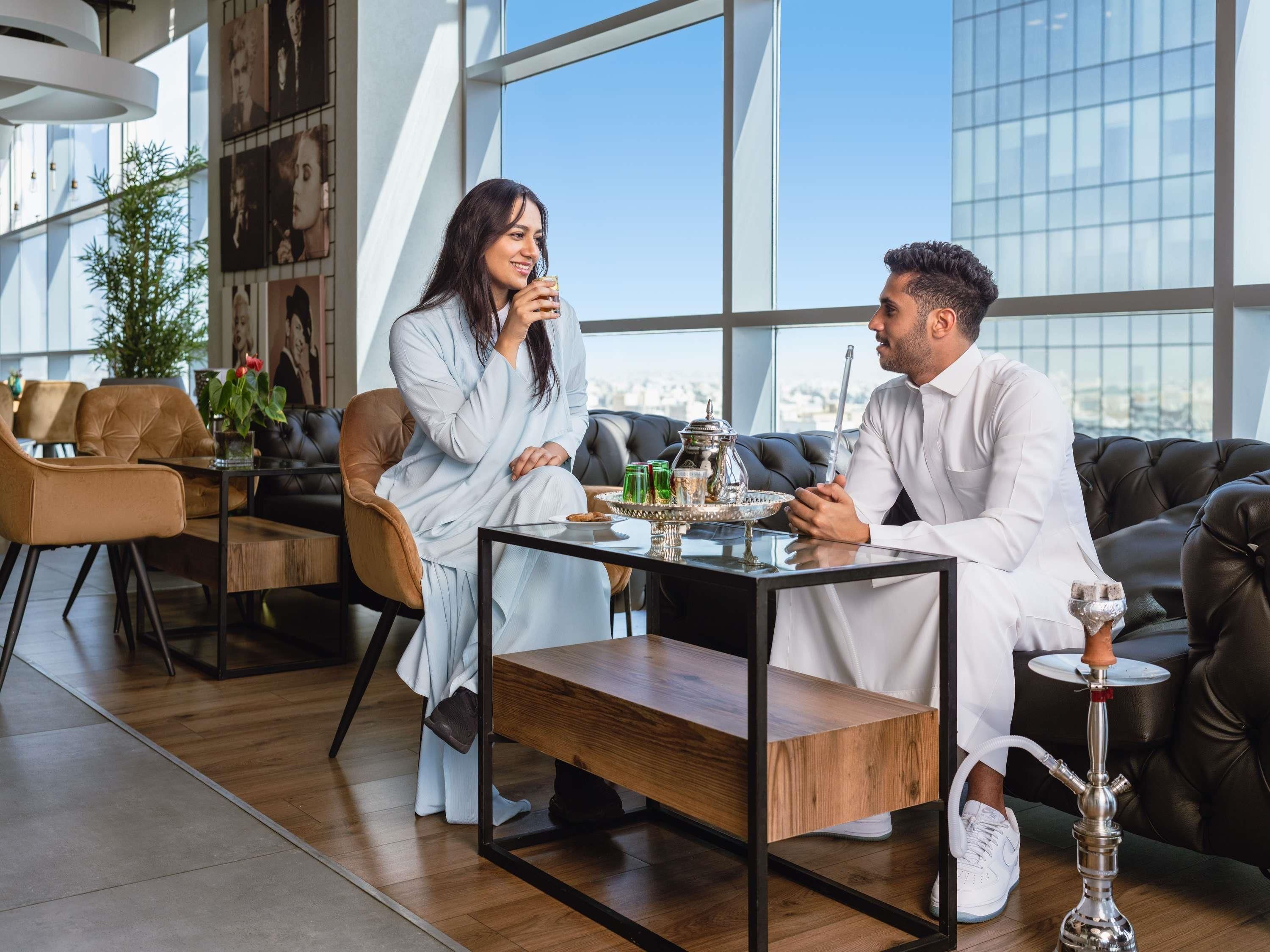 A modern interior with a leather couch, a wooden coffee table, and a hookah on a side table.