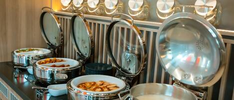 A buffet setup with various food items in stainless steel containers, a radiator, and wall-mounted lights.