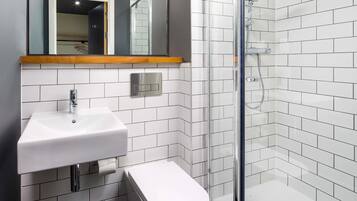 A modern bathroom with a glass-enclosed shower, a white sink, and a toilet.