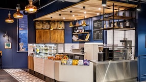 A modern kitchen with wooden cabinets, a stainless steel counter, and hanging pendant lights. - ibis Budget Sheffield Centre St Marys Gate (Sheffield)