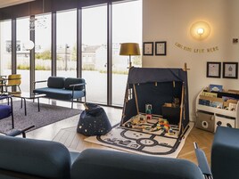 Une pièce accueillante avec un espace de jeux, des sièges et une vue dégagée grâce à de grandes fenêtres.
