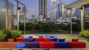 Terraza en la azotea con mobiliario exterior, vistas a un horizonte urbano y arquitectura moderna.