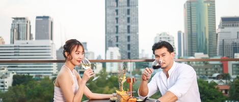 A couple seated at a table with a city skyline in the background.