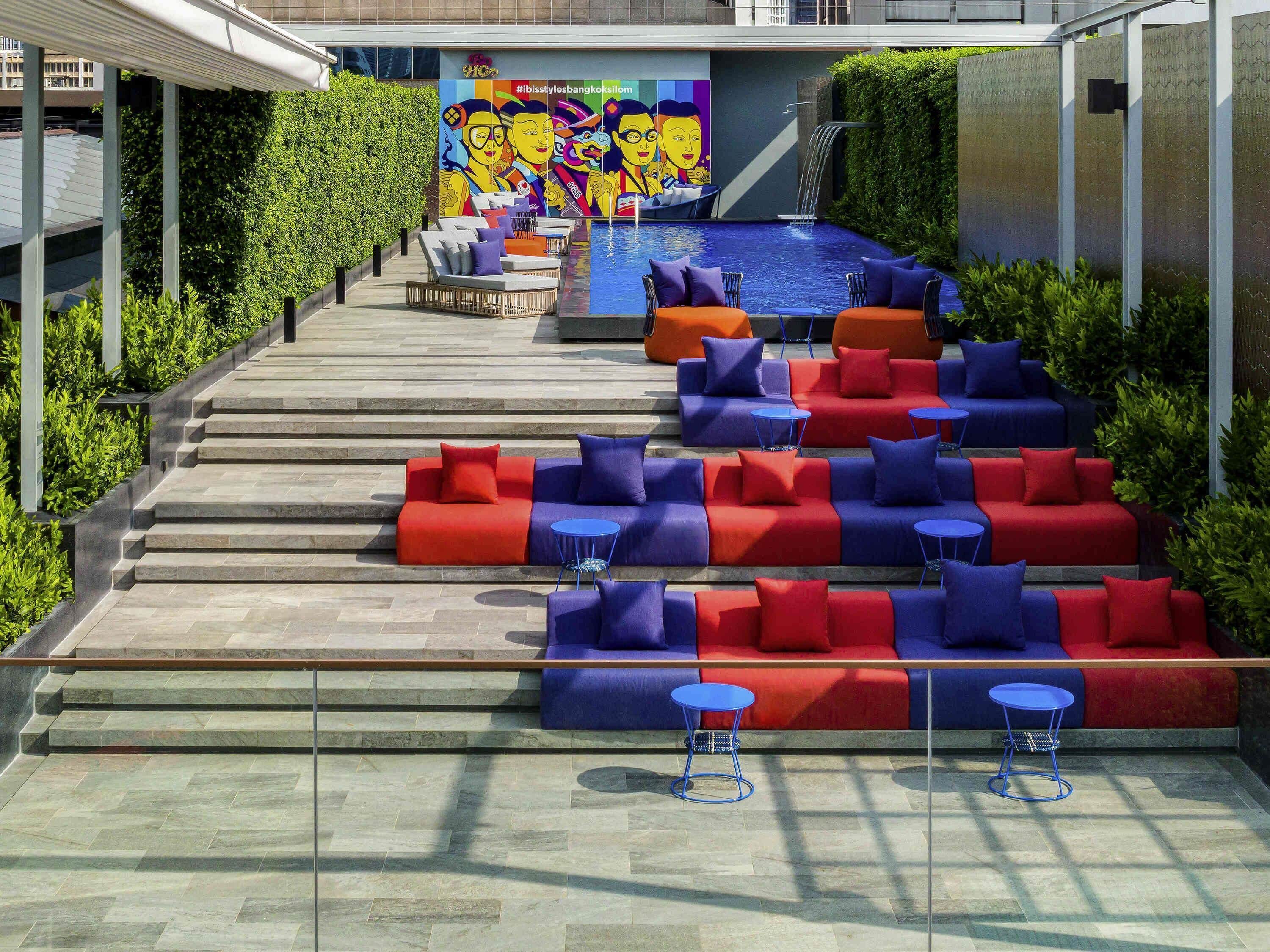 A poolside area with tiered seating and a mural in the background.