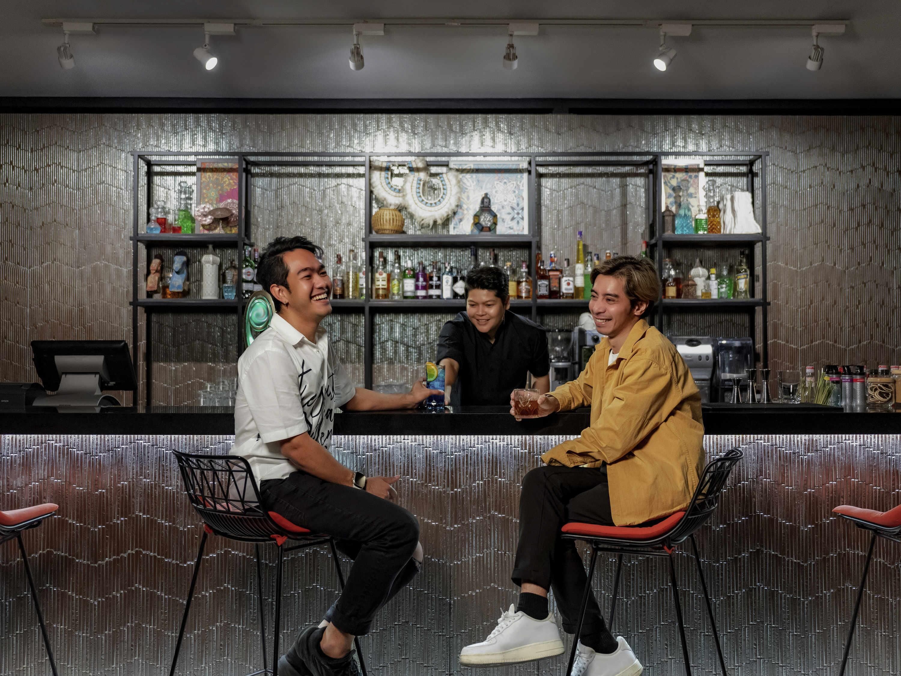 A bar area with stools, shelves with bottles, and a cash register.