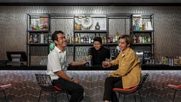 A bar area with stools, shelves with bottles, and a cash register.