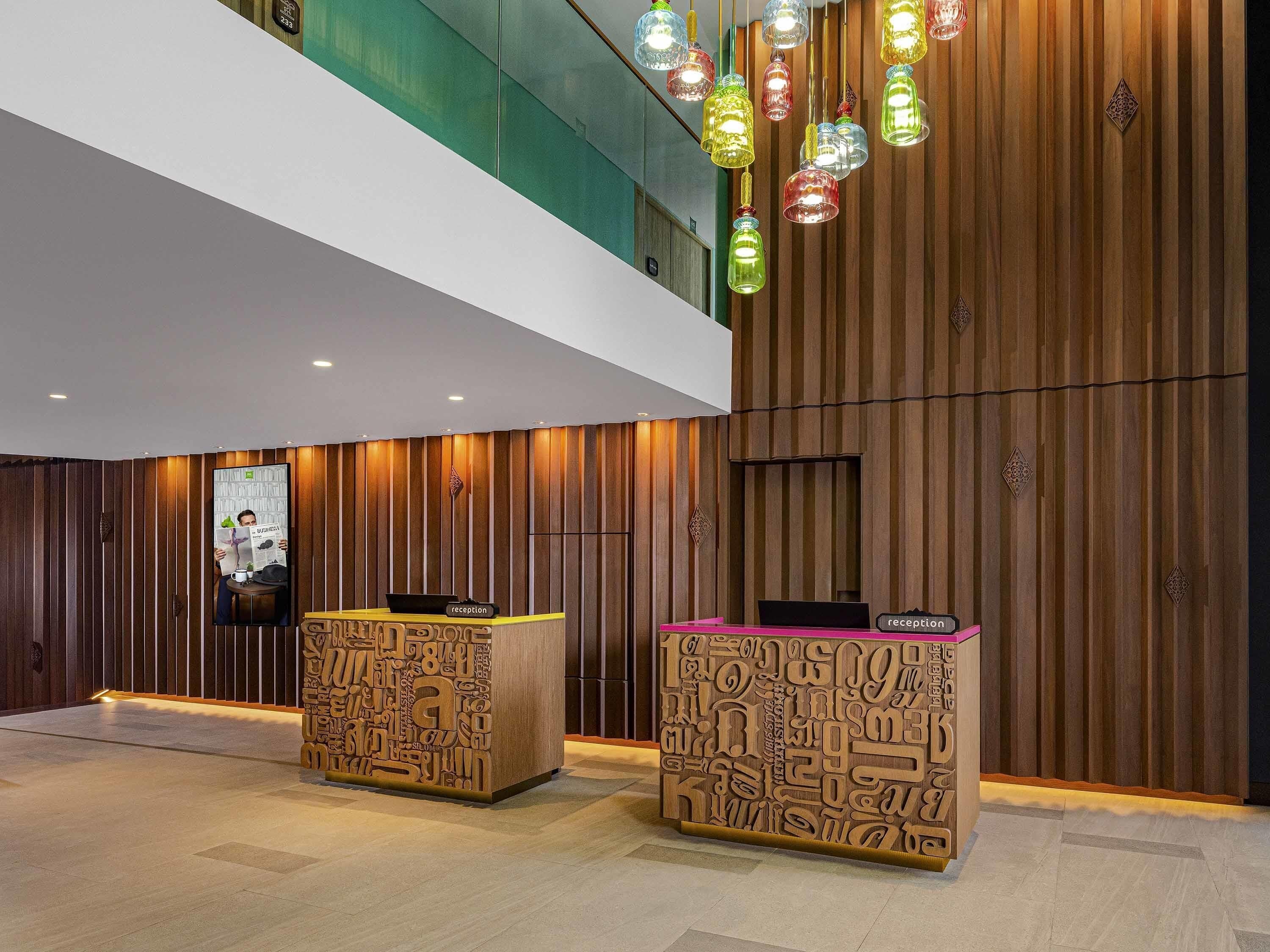 A reception area with wooden paneling, two reception desks, and colorful hanging lights.