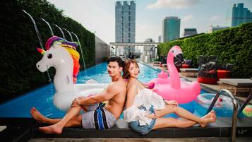 Relax by the pool with a city view, surrounded by lush greenery and fun pool toys.