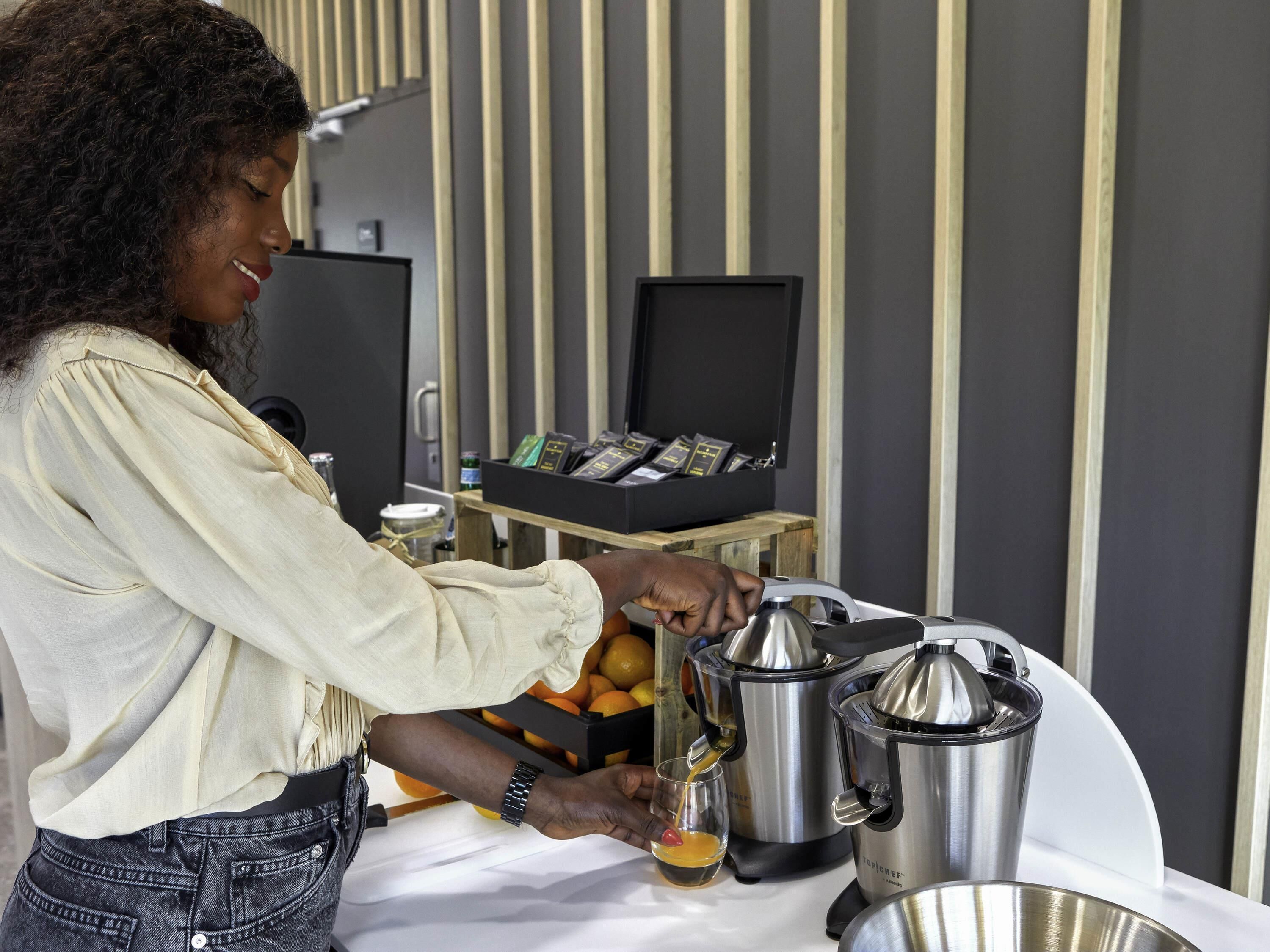 Una persona preparando una bebida con un exprimidor y un vaso sobre una mesa.