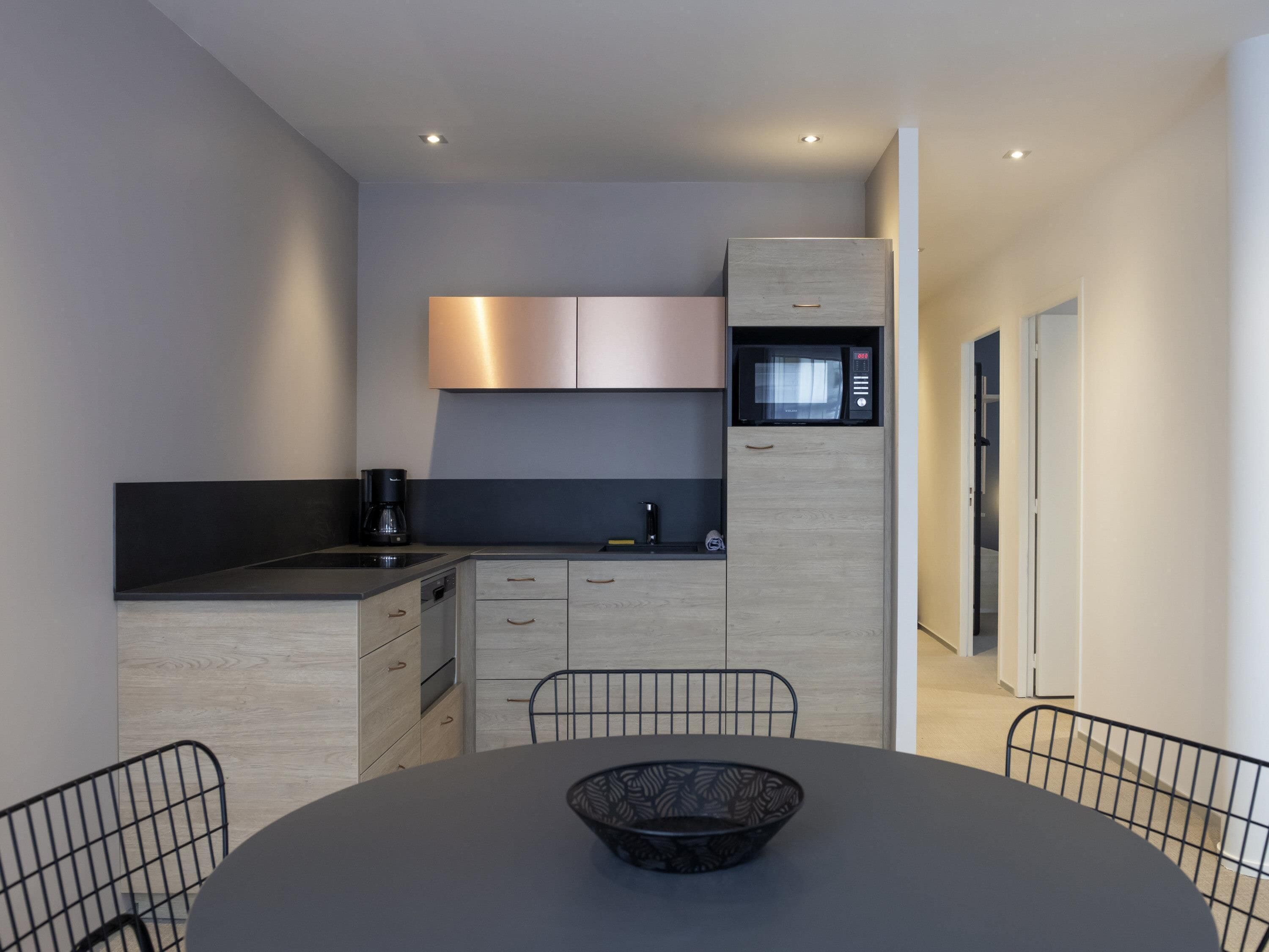 A modern kitchen with a built-in microwave, a coffee maker, and a dining area with a table and chairs.