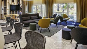Un espacio lounge moderno con mesa de billar, asientos cómodos y amplios ventanales que ofrecen vistas al exterior.