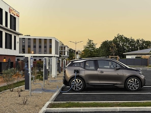 A car charging at a station with a building in the background.