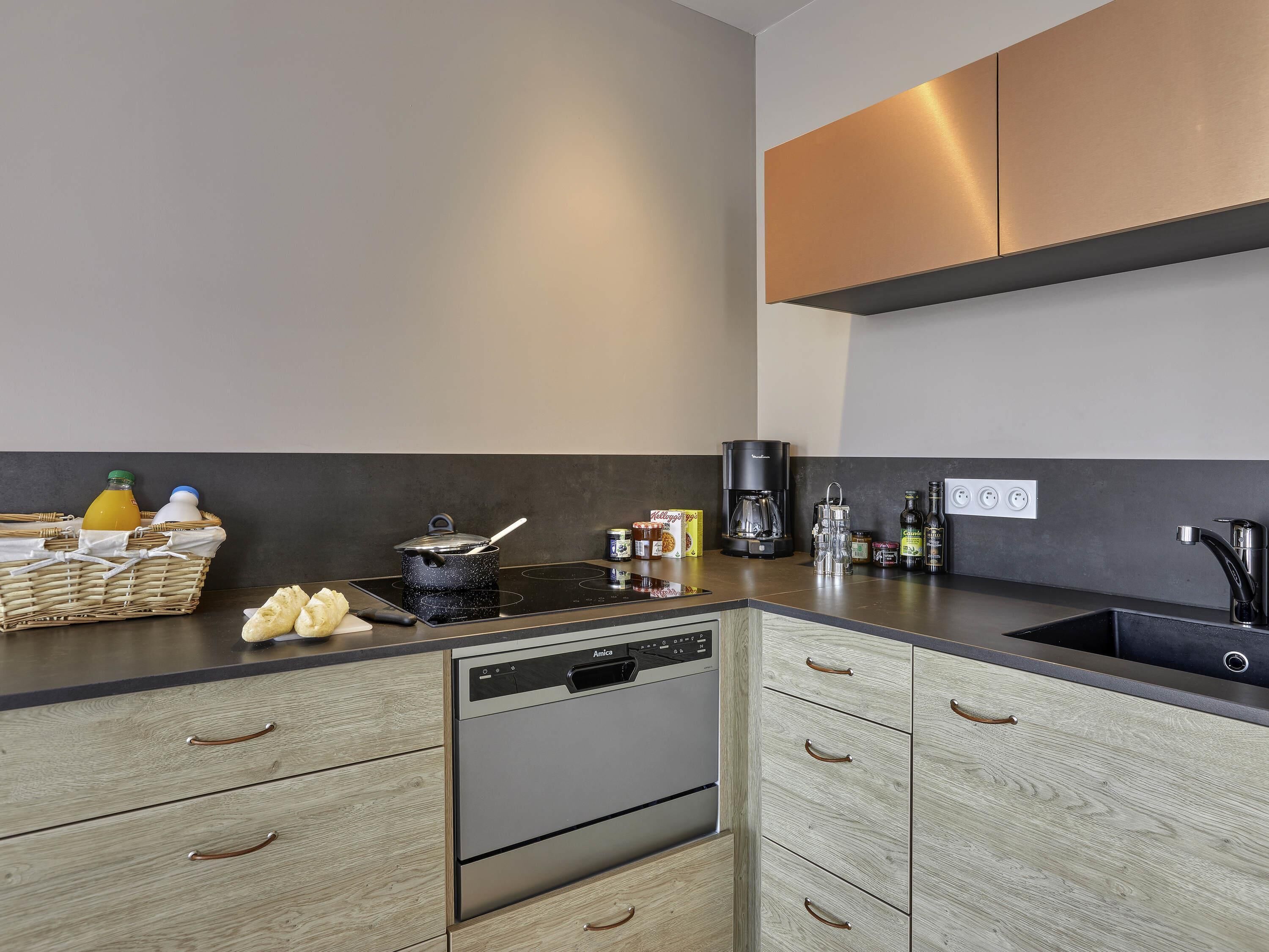 Una cocina moderna equipada con lavavajillas integrado, cafetera y diversos electrodomésticos.