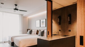 Una habitación de hotel moderna con una cama grande, tocador incorporado y ventilador de techo.