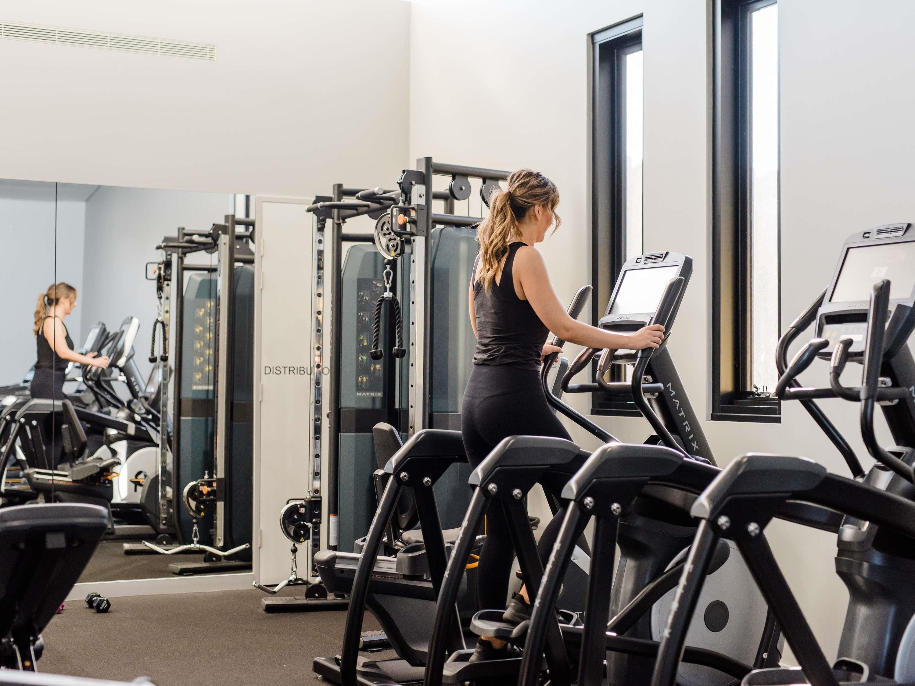 Academia com esteiras, aparelhos de musculação e espelho.