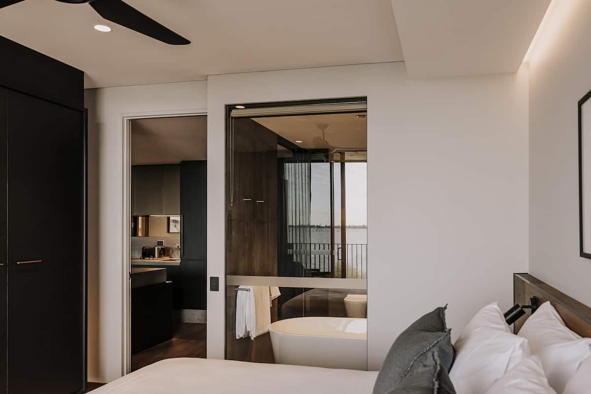 Ein modernes Hotelzimmer mit Bett, Bad, Küchenzeile und Balkon mit Blick.