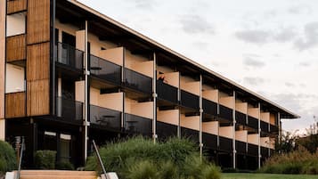 Un edificio moderno de varios pisos con techo plano, balcones y una escalera que conduce a la entrada.