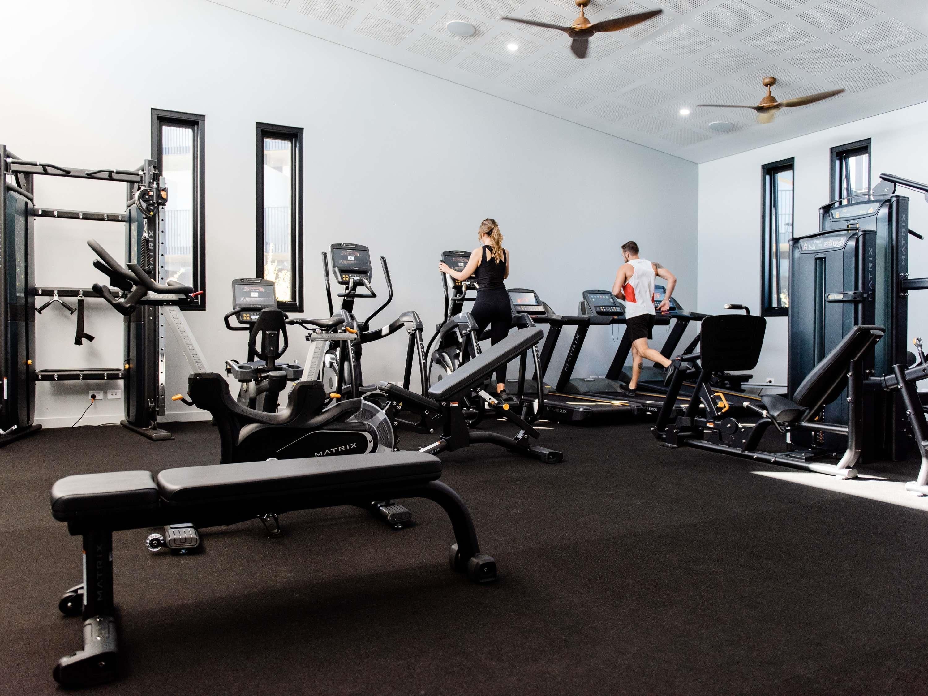 Ett gym med löpband, styrketräningsmaskiner och en bänk.