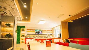 Un espace repas moderne avec une longue table, des chaises et un écran de télévision.