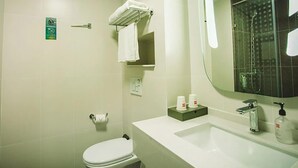 Une salle de bain comprenant des toilettes, un lavabo, un miroir, un porte-serviettes et une cabine de douche en verre.