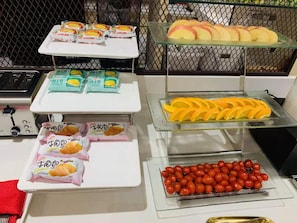 A buffet with various food items including packaged snacks, sliced fruits, and cherry tomatoes. - Ibis Dalian Xinghai Park (Dalian)