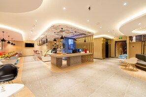 A modern hotel lobby with a reception desk, seating area, and a large screen displaying information. - Ibis Dalian Xinghai Park (Dalian)