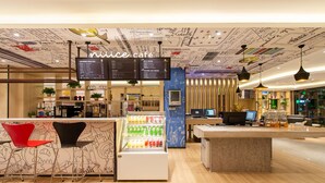 Een modern café met een menubord, een zithoek en een drankendisplay.