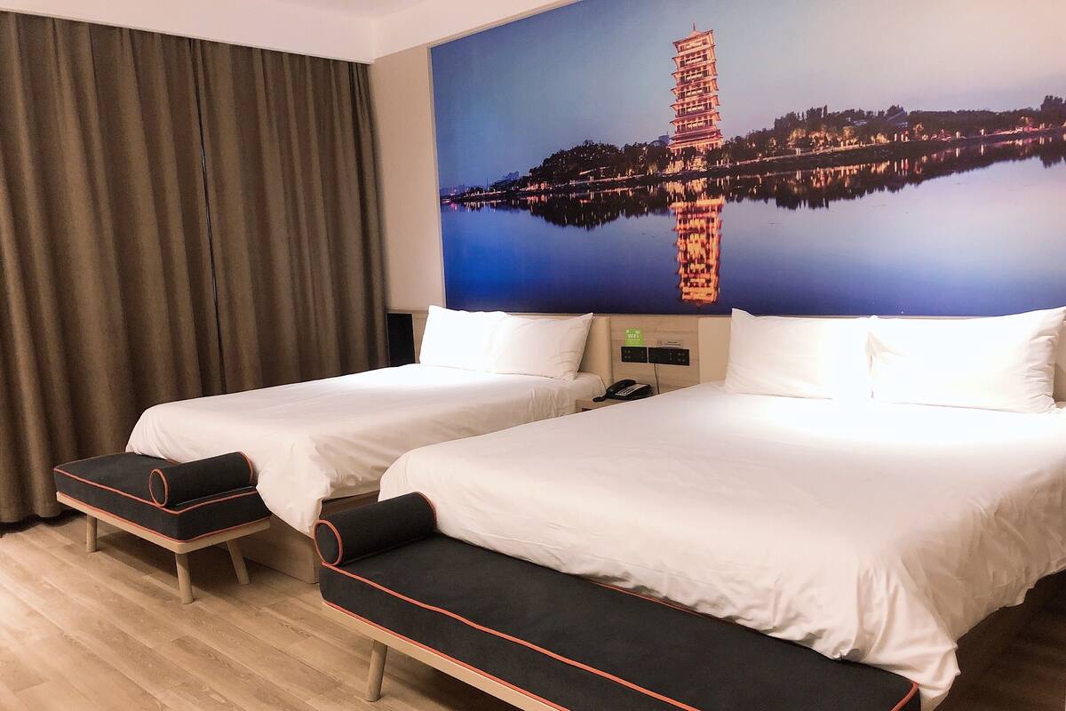 A hotel room with two beds, a large window with a view of a pagoda, and a curtain.