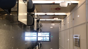Une salle de conférence moderne, dotée de rangées de chaises, d’une grande fenêtre et de luminaires fixés au plafond.